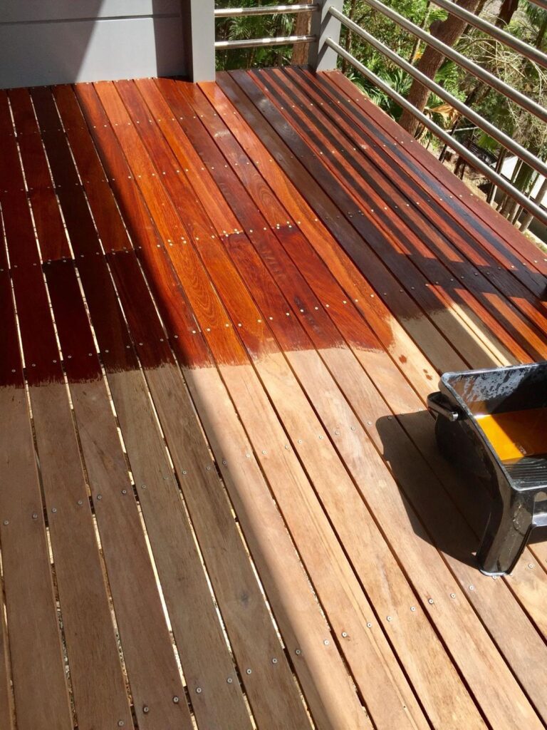 Close-up of the wood staining process showing the transformation from raw timber to a glossy, protected finish.
