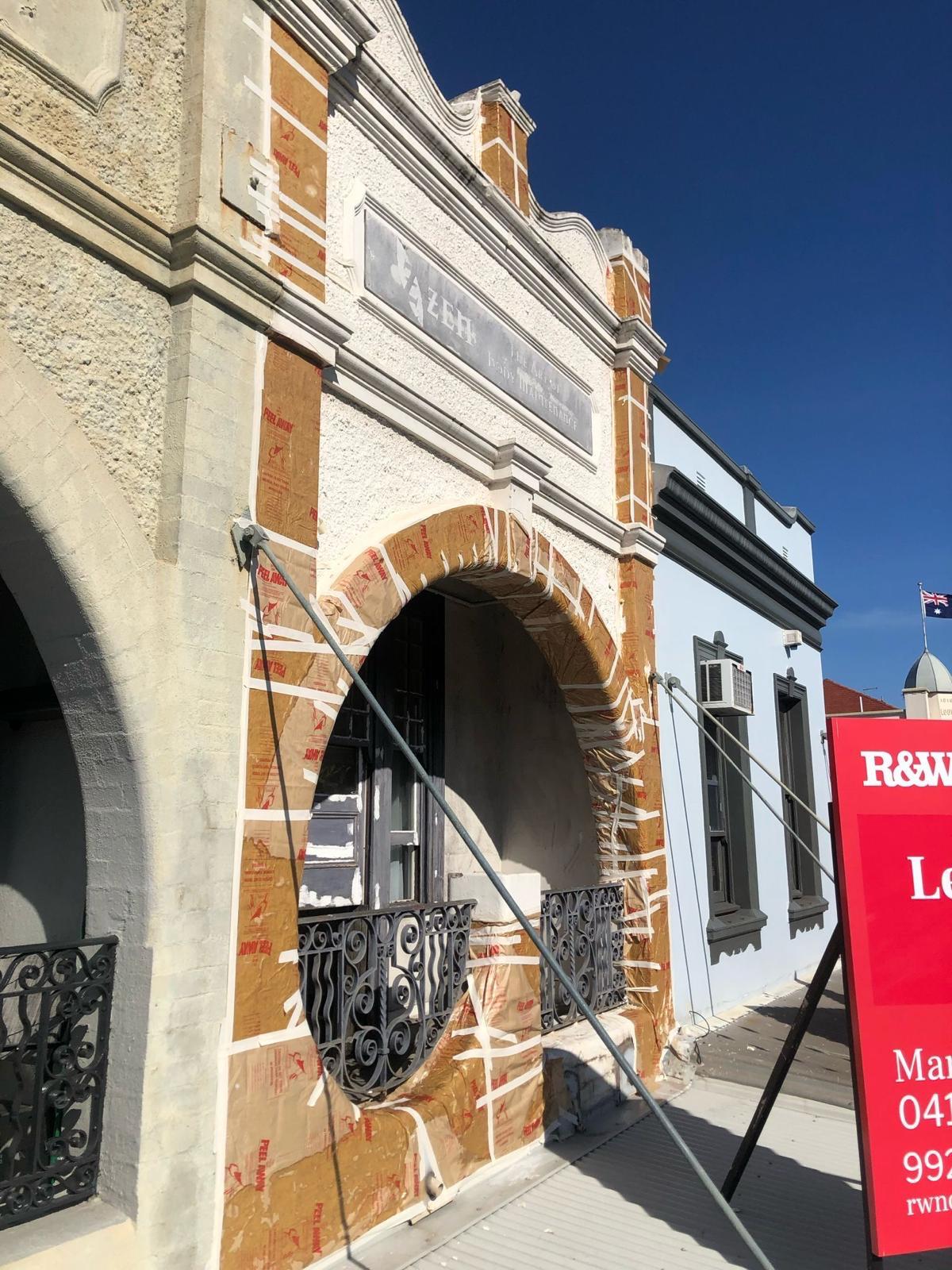 Detailed surface preparation and masking on a heritage building facade to ensure a clean professional paint finish