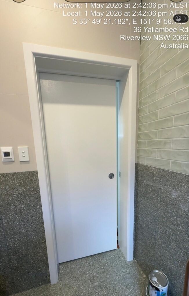 Professional interior white door and frame painting in a modern bathroom featuring grey textured walls and tiling