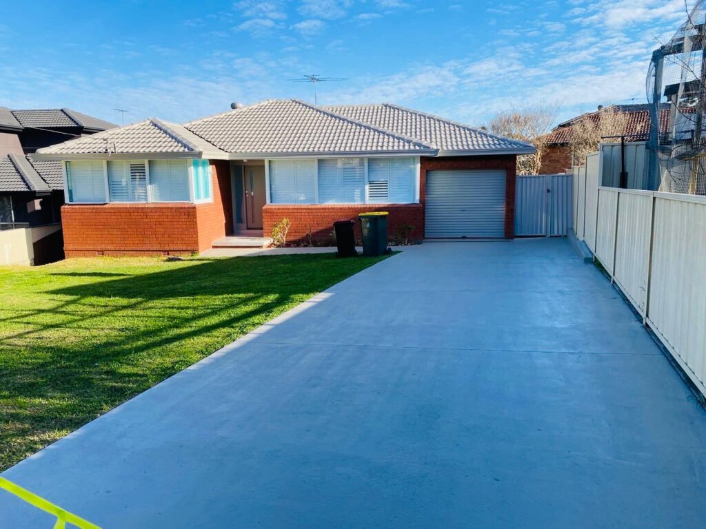 Freshly painted light grey concrete driveway for a modern brick residential home in Sydney