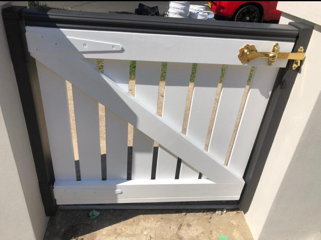 Freshly painted white timber garden gate with gold hardware and a dark grey top rail in a Sydney residence